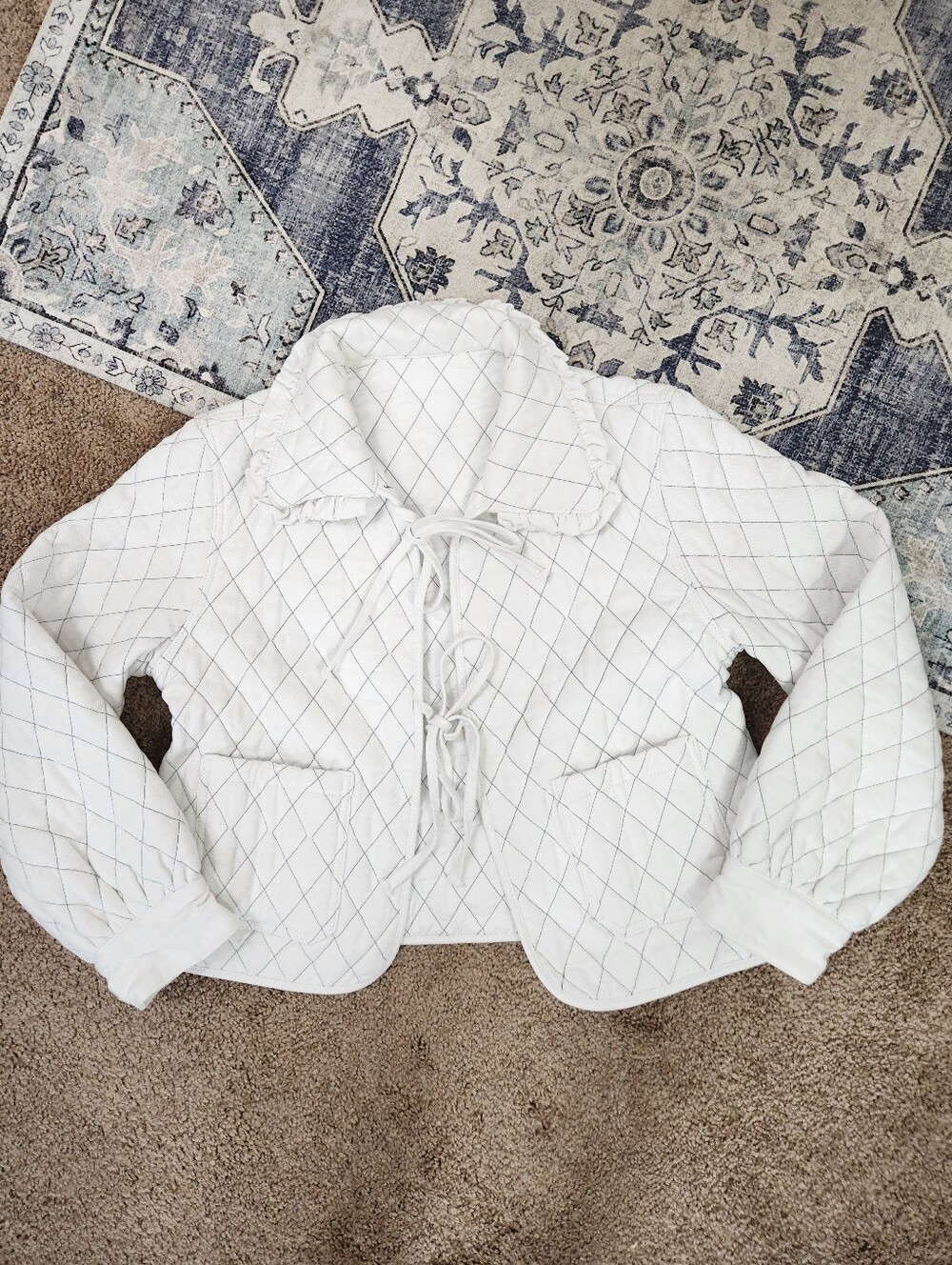 White quilted diamond pattern jacket with ruffle collar and tie front